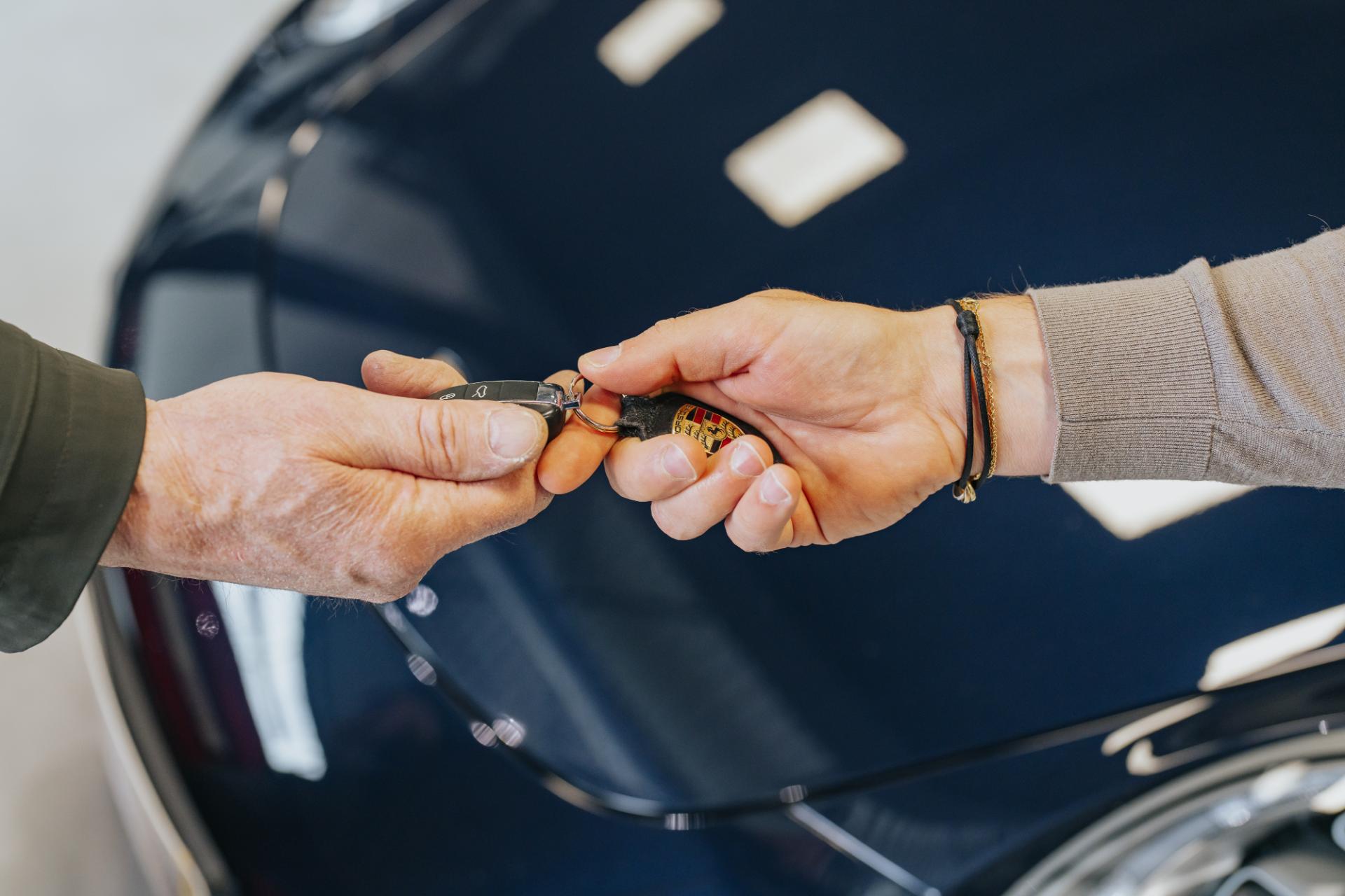 Close-up van sleuteloverdracht bij sportwagen aankoop
